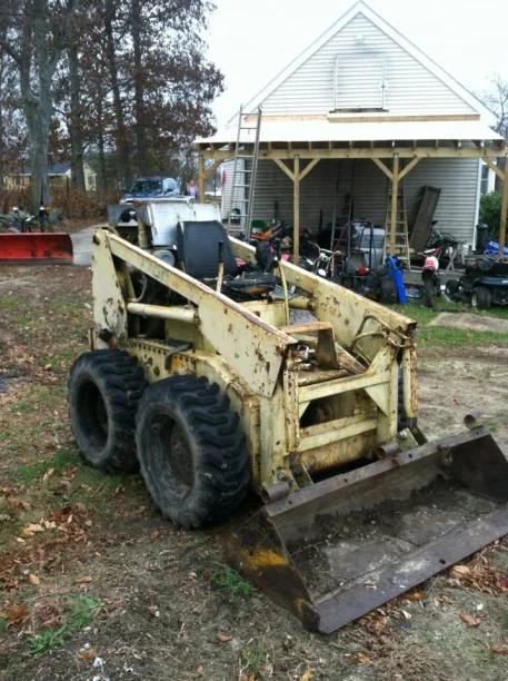 Older Mustang skid steer with bucket in a yard