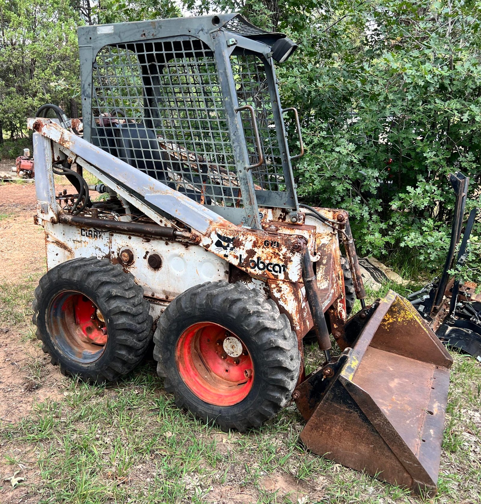 Used skid steer with bucket parked near a home garage