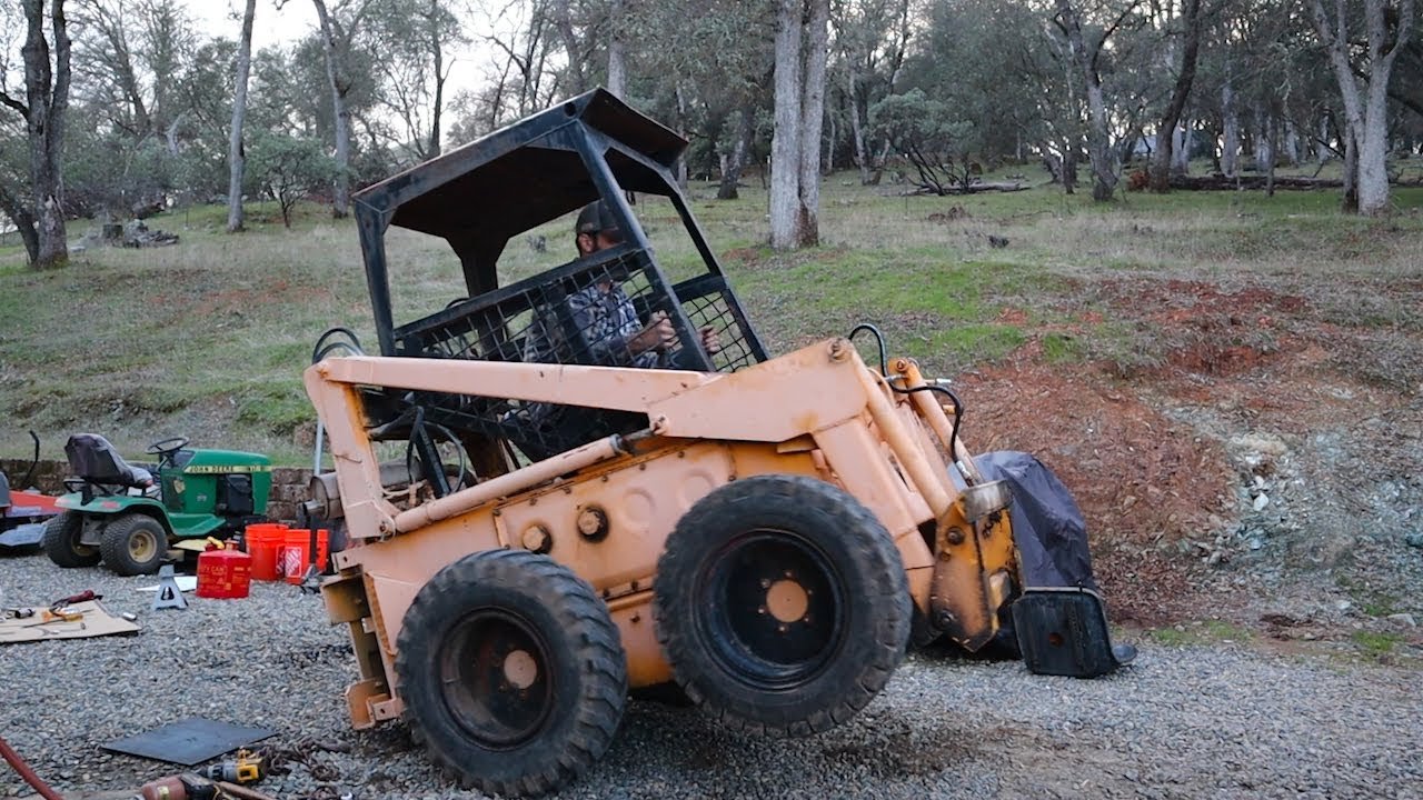 Non-running skid steer being loaded or recovered on gravel
